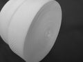 Two roll of white ribbon on a gray background