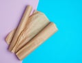 Two rolled rolls of brown parchment baking paper on a colored background