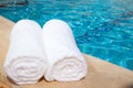 Two rolled-up white towels by blue pool