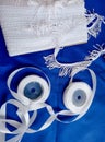 Two rolls of white ribbon and tassel on a bright blue cloth