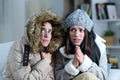 Two roommates shivering in a cold winter day at home Royalty Free Stock Photo
