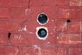 Two round electrical outlet boxes without wires mounted inside dilapidated red brick wall