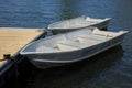 two rowboats on the edge of a dock on a calm lake aluminum boats recreation Royalty Free Stock Photo