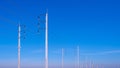 Two rows of electric poles with cable lines against blue sky background, low angle and perspective side view Royalty Free Stock Photo