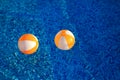 Two rubber air yellow white inflatable balls and toy for swimming pool in transparent blue water. Beach balls floating on water. Royalty Free Stock Photo