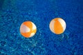 Two rubber air yellow white inflatable balls and toy for swimming pool in transparent blue water. Beach balls floating on water. Royalty Free Stock Photo