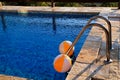 Two rubber air yellow white inflatable balls and toy for swimming pool in transparent blue water. Beach balls floating on water. Royalty Free Stock Photo