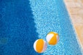 Two rubber air yellow white inflatable balls and toy for swimming pool in transparent blue water. Beach balls floating on water. Royalty Free Stock Photo