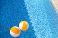 Two rubber air yellow white inflatable balls and toy for swimming pool in transparent blue water. Beach balls floating on water. Royalty Free Stock Photo