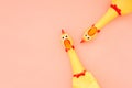 Two Rubber Chicken Toys on a pastel pink Background and Copyspace. Screaming rubber chicken toy on coral background