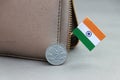 Two Rupee money coin of India and mini Indian flag stick on the leather wallet on grey background