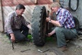 Two russian farmers repair wheel in the territory farm garage.