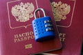 Two Russian passports on blue padlock. Wooden background. Closeup