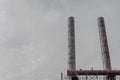 Two rusted metal smokestacks against a dark gray sky, copy space
