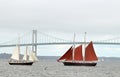 Two sailboat with red and white sails and Newport Bridge