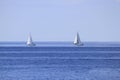 Two sailboats on open sea horizon