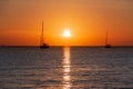 Two sailboats sailing across the ocean against a golden sunset Royalty Free Stock Photo