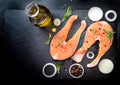 Salmon steak, pepper and salt, herbs on black stone concrete table, copy space top view Royalty Free Stock Photo