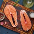 Two salmon steaks, fish fillet, large sliced portions  on chopping board on a dark table. Top view, close up Royalty Free Stock Photo