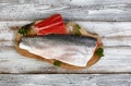 Two Salmon trout fillet, skin side up and down, on natural olive wood server with parsley and salt seasonings