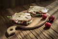 two sandwiches with cheese, ham and lettuce on a cutting board on a wooden background lit by natural morning light from the window Royalty Free Stock Photo