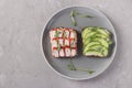 Two sandwiches on toast with cream cheese, cucumbers and crab sticks decorated with microgreens peas on a plate on gray concrete