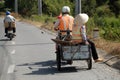 Two sanitation worker moving on country road together, man ride motorbike with drag box transfer woman Royalty Free Stock Photo
