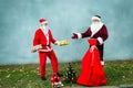 Two Santa Claus collect a big bag of gifts for Christmas. Royalty Free Stock Photo