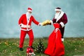 Two Santa Claus collect a big bag of gifts for Christmas. Royalty Free Stock Photo