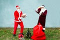 Two Santa Claus collect a big bag of gifts for Christmas. Royalty Free Stock Photo