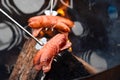 Two sausages on metal forks over outdoor camp fire