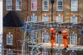 Two scaffolders working on a building site, wearing orange hi-vis protection clothes. Royalty Free Stock Photo
