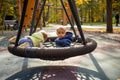 Two scared toddlers boy and girl left unattended are sitting on a swing hammock on a playground in the autumn park Royalty Free Stock Photo