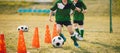 Two school boys running and kicking soccer balls between training cones Royalty Free Stock Photo