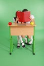 Two school girl sharing secrets sitting at a desk from book