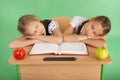 Two school girls sleeping on a stack of books at her desk Royalty Free Stock Photo