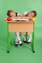 Two school girls sleeping on a stack of books at her desk Royalty Free Stock Photo