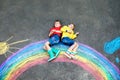 Two school kids boys having fun with with rainbow picture drawing with colorful chalks on asphalt. Siblings, twins and Royalty Free Stock Photo