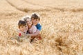 Two school kids boys and little sister, preschool girl hugging on wheat field. three happy children playing together and having Royalty Free Stock Photo