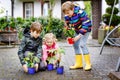 Two school kids boys and little toddler girl with tomato and cucumber seedings. Three children gardening in spring on Royalty Free Stock Photo