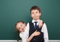 Two school student posing at the clean blackboard, grimacing and emotions, dressed in a black suit, education concept, studio Royalty Free Stock Photo