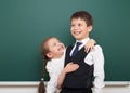 Two school student posing at the clean blackboard, grimacing and emotions, dressed in a black suit, education concept, studio Royalty Free Stock Photo