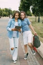 Two schoolgirls are holding a tablet in their hands and watching a video, laughing on the way to school. Friends Royalty Free Stock Photo