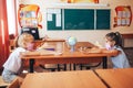 Two schoolgirls in medical masks are sitting at a school desk, opposite each other, group session, back to school, teaching
