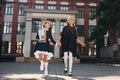 Two schoolgirls is running outside together near school building Royalty Free Stock Photo