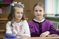 Two schoolgirls sit at a desk in the classroom Royalty Free Stock Photo