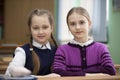 Two schoolgirls sit at a desk in the classroom Royalty Free Stock Photo