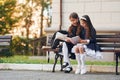 Two schoolgirls is sitting outside together near school building Royalty Free Stock Photo