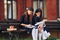 Two schoolgirls is sitting outside together near school building Royalty Free Stock Photo