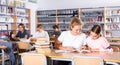 Two schoolgirls take notes in a exercise book of the necessary material from the textbook